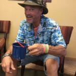 Senhor idoso alegre sentado em uma cadeira com uma xícara de café
