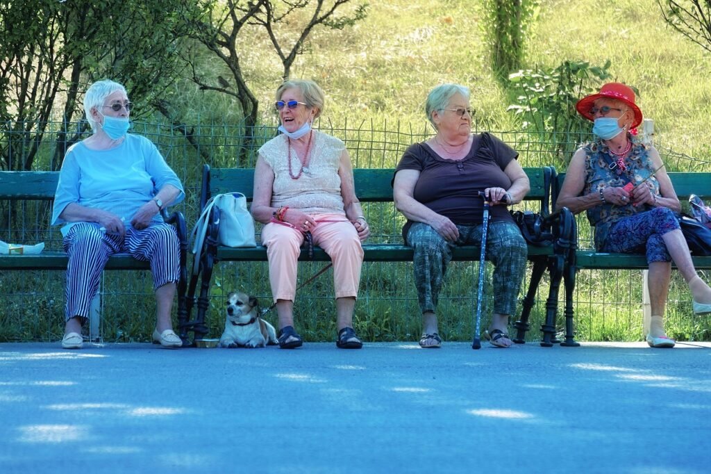 Senhoras idosas sentadas no banco da parque conversando e passeando com seus pets