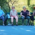 Senhoras idosas sentadas no banco da parque conversando e passeando com seus pets