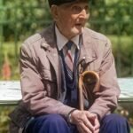Senhor idoso sentado no banco da praça sozinho