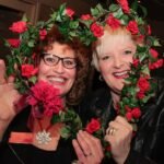Duas senhoras idosas sorrindo segurando um coração de flores