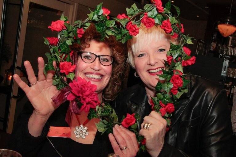 Duas senhoras idosas sorrindo segurando um coração de flores