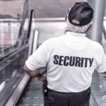 Idoso segurança de um shopping descendo a escada rolante